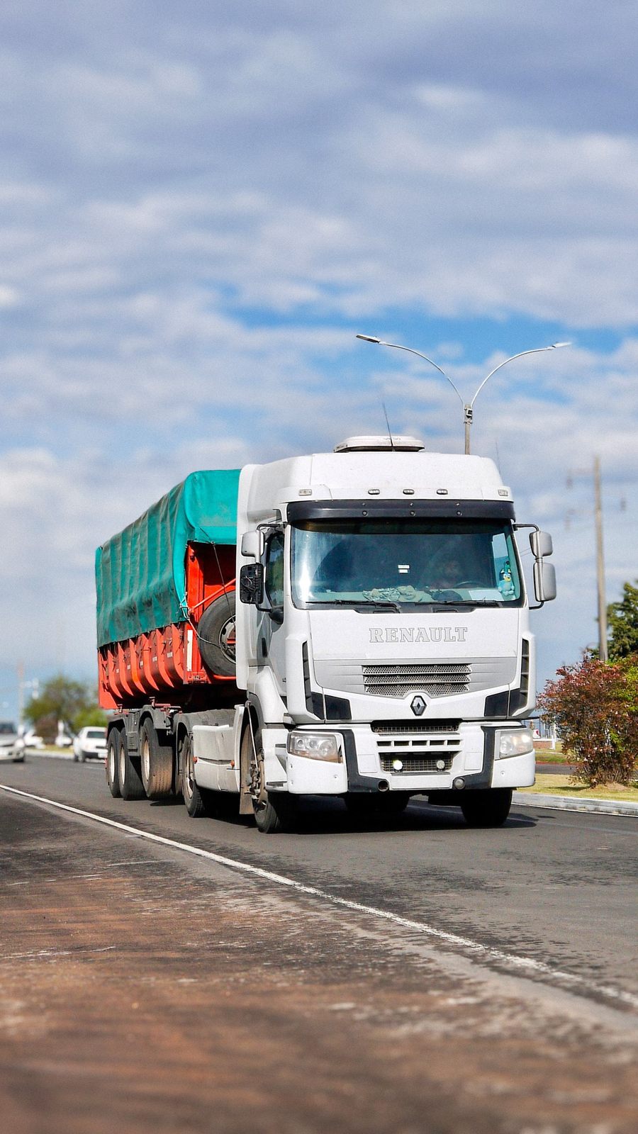 A white cargo truck travels on a highway under a bright blue sky, illustrating transportation and logistics